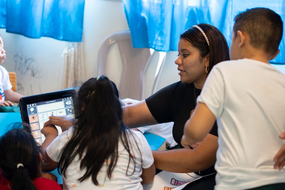 Teacher of the Nazareth School in olancho honduras using a AAC device with students speech impediments and with disabilities
